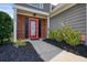 Charming entry with a red glass front door, black shutters, mulch flower beds and green bushes at 1265 Birchwood Ln, Roswell, GA 30076