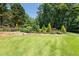 This backyard has professionally designed tiered landscaping with mature trees and lush green lawn at 619 Lovinggood Trl, Woodstock, GA 30189