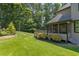 A view of the backyard features beautiful landscaping, a screened in porch, and lush green lawn at 619 Lovinggood Trl, Woodstock, GA 30189