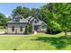 Two story home with stone and neutral tone siding surrounded by green trees at 619 Lovinggood Trl, Woodstock, GA 30189