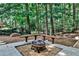 Backyard firepit area featuring built-in benches and mature landscaping at 10575 Tuxford Dr, Alpharetta, GA 30022