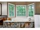 Relaxing bathroom showcases a large soaking tub with surrounding tile and natural light from bay windows at 10575 Tuxford Dr, Alpharetta, GA 30022