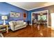Comfortable living room showcasing hardwood floors, blue walls, and an open layout to the dining area at 10575 Tuxford Dr, Alpharetta, GA 30022