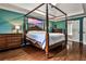 Spacious main bedroom with hardwood floors, four-poster bed, and ensuite bathroom creating a luxurious retreat at 10575 Tuxford Dr, Alpharetta, GA 30022