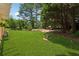 Expansive backyard featuring manicured lawn, mature trees, and a charming bird bath feature at 1125 Fairview Club Cir, Dacula, GA 30019