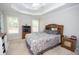 Comfortable bedroom featuring a decorative tray ceiling, dresser, and windows at 241 Lost Lake Way, Villa Rica, GA 30180