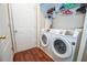 This laundry room features a white washer and dryer set, adjacent to a door with wooden floors and a closet with overhead shelving at 241 Lost Lake Way, Villa Rica, GA 30180