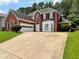 Charming two-story red brick home with a well-manicured lawn and a curved driveway at 134 Carolinas Way, Fayetteville, GA 30215