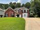 Charming two-story red brick home with a well-manicured lawn and a curved driveway at 134 Carolinas Way, Fayetteville, GA 30215