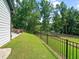 Spacious backyard with a black fence, lush lawn, mature trees, a hot tub, and ample space for outdoor activities at 3640 Pollys Blf, Cumming, GA 30028