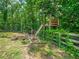 Backyard with a custom-built treehouse and rustic wooden fence amid lush greenery at 3640 Pollys Blf, Cumming, GA 30028