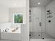 Bright bathroom features a garden tub, walk-in shower with glass door and white subway tile at 3640 Pollys Blf, Cumming, GA 30028