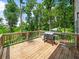 Overlooking lush greenery, this spacious wooden deck is equipped with a grill for outdoor entertainment at 3640 Pollys Blf, Cumming, GA 30028