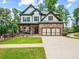 Two story home featuring a stone facade, a cozy front porch, an expansive lawn, and a two car garage at 3640 Pollys Blf, Cumming, GA 30028