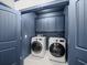 Laundry room with washer, dryer, and navy cabinets for ample storage at 3640 Pollys Blf, Cumming, GA 30028