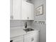 This laundry room has white cabinets, quartz countertops, stainless steel sink and playful decor at 3640 Pollys Blf, Cumming, GA 30028