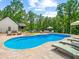 Sparkling backyard pool surrounded by a stone patio, lounge chairs, and lush green trees at 3640 Pollys Blf, Cumming, GA 30028