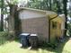 Shows the brick facade and vinyl siding with two trash receptacles and overgrown vegetation at 5114 Fawn Se Trl, Mableton, GA 30126