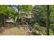 Aerial view of the serene backyard with mature trees, lush landscaping, patio, and firepit area at 1788 River Bluff Vw, Duluth, GA 30097