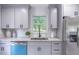 Close up of kitchen with gray cabinets, stainless steel refrigerator and sink, and a pop of blue from the dishwasher at 243 Hickory Way, Canton, GA 30115
