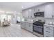 Bright, open concept kitchen with gray cabinets, stainless appliances, view of dining room, and wood grain floors at 243 Hickory Way, Canton, GA 30115