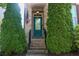 A stylish turquoise front door framed by lush greenery and elegant brickwork at 7825 Crownpoint Dr, Alpharetta, GA 30005