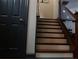 Staircase with wooden steps, contrasting black door, and wrought iron banister at 7825 Crownpoint Dr, Alpharetta, GA 30005