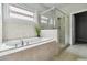 Bright bathroom features a large window, tiled surround soaking tub, and separate glass-enclosed shower at 4808 Albany Way, Atlanta, GA 30331