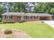 Charming brick home with manicured lawn, black shutters, and covered carport at 4077 Phils Ct, Tucker, GA 30084