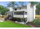 Backyard featuring covered patio, elevated deck with steps, well-manicured lawn, and white painted brick chimney at 4555 Holliston Rd, Dunwoody, GA 30360
