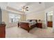 Spacious main bedroom features a tray ceiling, ceiling fan, and a view into the ensuite bathroom at 8295 Village Pl, Suwanee, GA 30024