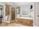 Elegant bathroom with a soaking tub, glass-enclosed shower, and decorative window at 1140 River Laurel Dr, Suwanee, GA 30024