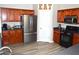 Open kitchen with stainless steel appliances, brown cabinets, and wood-look flooring at 2481 Southhaven Ln, Buford, GA 30519