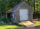 Outdoor shed featuring a garage door, ramp, and garden decor at 969 Golden Meadows Ln, Loganville, GA 30052