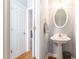 Stylish powder room with a pedestal sink, decorative mirror, and white door at 1469 Crescent Walk, Decatur, GA 30033