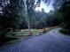 Picturesque gravel driveway flanked by a wooden fence with lighted posts leading to a private wooded property at 5491 Hiram Rd, Powder Springs, GA 30127