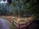 Long, gravel driveway with wooden fence posts and yard lights leading to a private wooded property at 5491 Hiram Rd, Powder Springs, GA 30127
