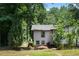 Rear view of a white home with black trim and new landscaping surrounded by lush trees, enhancing its privacy at 3267 Sunderland Dr, Snellville, GA 30039