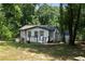 Charming single-story home featuring white siding, black trim, and a cozy front deck surrounded by lush greenery at 3267 Sunderland Dr, Snellville, GA 30039