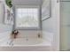 Bright bathroom features a soaking tub with chrome faucet and a tiled surround at 3370 Battlement Cir, Loganville, GA 30052