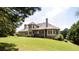 Rear exterior view of home featuring a covered porch and well-manicured lawn blending into a serene wooded backdrop at 240 Chandler Walk, Loganville, GA 30052
