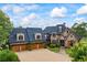 Elegant stone home showcasing a three-car garage and manicured landscaping at 4239 Lower Jersey Rd, Covington, GA 30014