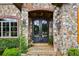 Elegant wrought-iron double doors framed by stone and brick, with mature landscaping at 4239 Lower Jersey Rd, Covington, GA 30014