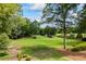 Lush green lawn with mature trees and plantings surrounding a serene pond or lake at 4239 Lower Jersey Rd, Covington, GA 30014