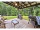 Relaxing covered patio with outdoor seating, a ceiling fan, a fire pit, and a grill overlooking a lush backyard at 404 Arden, Ellenwood, GA 30294