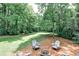 Spacious backyard with mature trees and a seating area around a fire pit at 437 Valley Brook Ne Dr, Atlanta, GA 30342