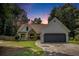 Charming home with a well-maintained lawn, stone accents, a gray two-car garage and lush landscaping at dusk at 2085 Castle Royale Dr, Lawrenceville, GA 30043