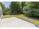 A grassy backyard with a concrete patio area in a fenced yard surrounded by mature trees at 706 Hillmont Dr, Loganville, GA 30052