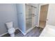 Well-lit bathroom featuring tiled shower with a glass door, commode, and gray vinyl flooring at 706 Hillmont Dr, Loganville, GA 30052