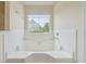 Bathroom featuring a garden tub, large window with blinds, and tiled walls at 2410 Napa Valley Dr, Villa Rica, GA 30180